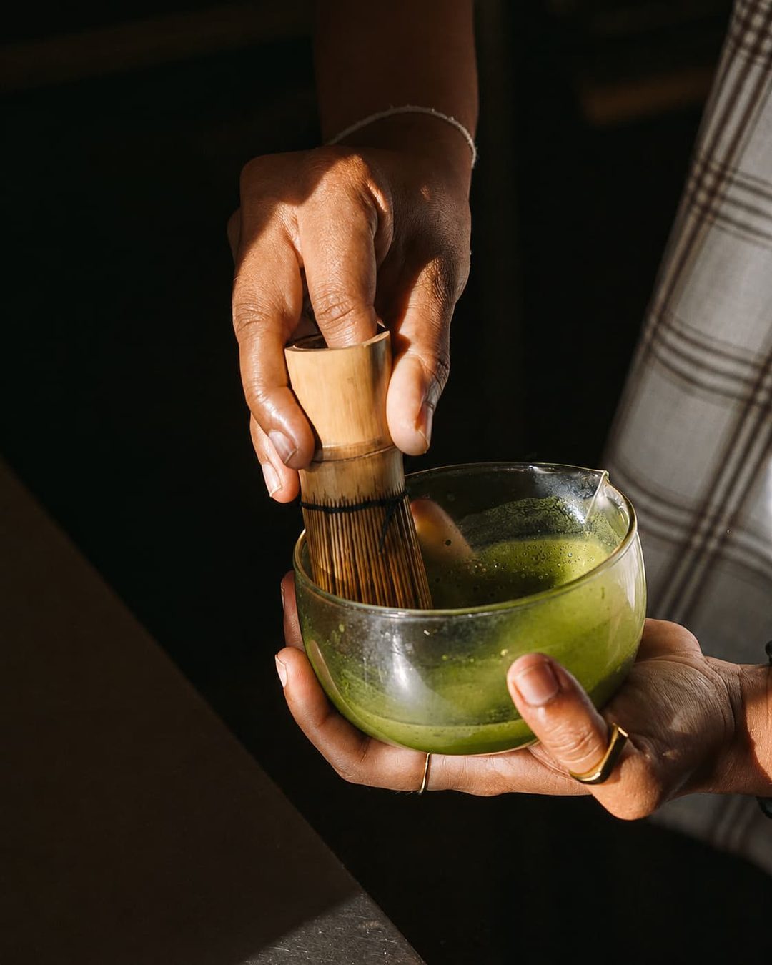 Matcha being whisked in a glass bowl with a bamboo chasen
