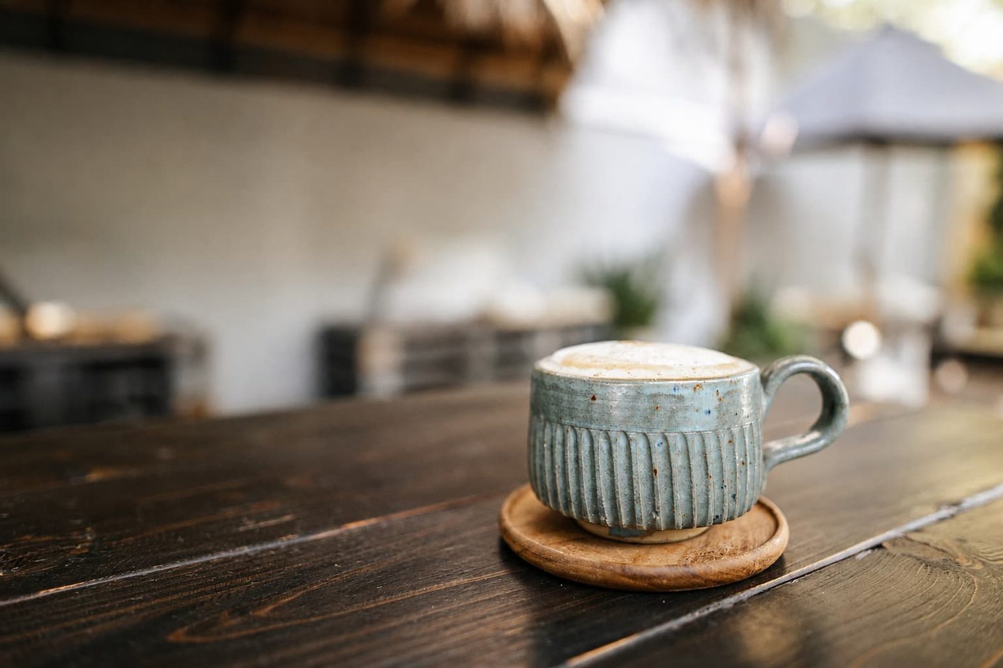 A ribbed stoneware cup of coffee on a dark wooden table